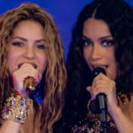 Shakira e Anitta cantando juntas ao microfone em um palco