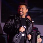 O cantor Xand Avião sorrindo com microfone na mão durante show